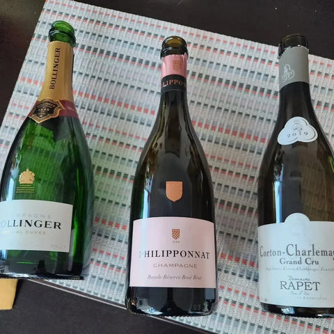 Bottles of Bollinger, Philipponnat, and Corton-Charlemagne displayed together at Community Wine & Spirits.