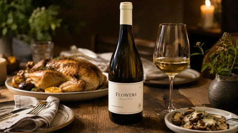Flowers Sonoma Coast Chardonnay from Community Wine & Spirits beside roast chicken and a glass of white wine.