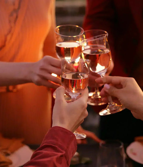 Friends toast with glasses of wine at a Community Wine & Spirits gathering.